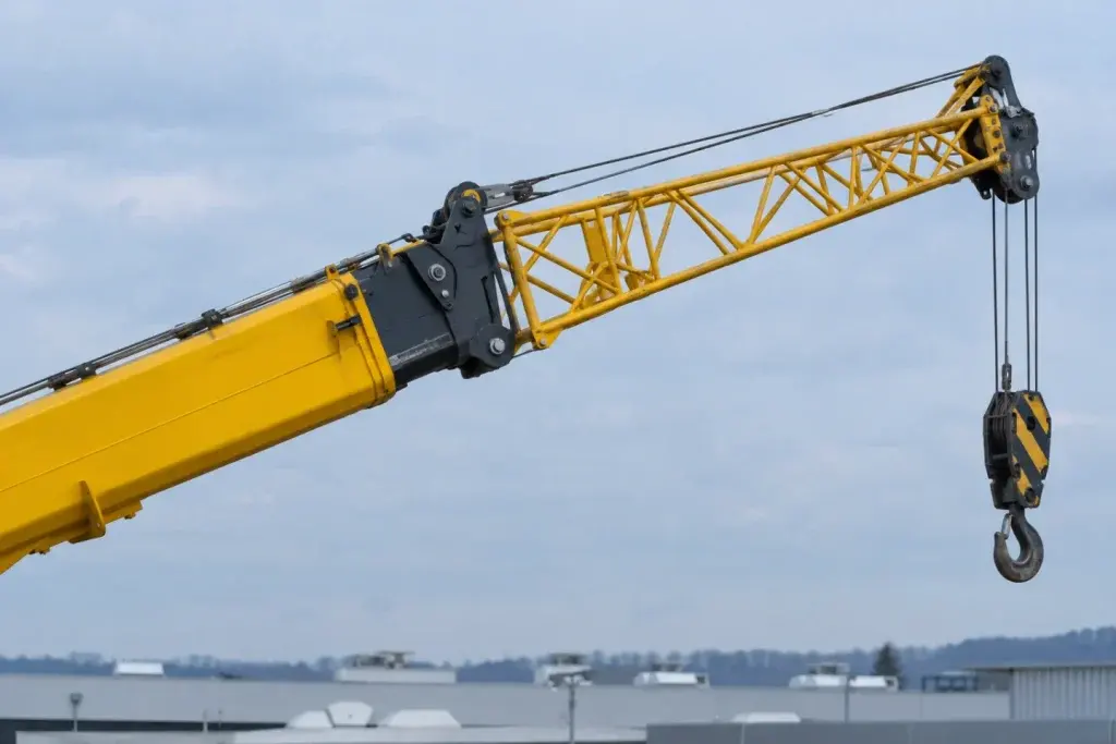 Đầu cần ống lồng màu vàng có phần cần phụ dạng giàn và móc trống trên nền trời