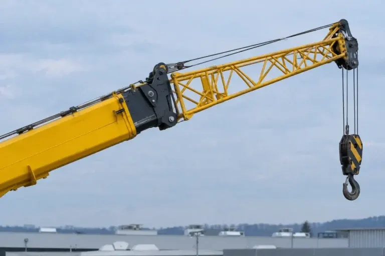 Đầu cần ống lồng màu vàng có phần cần phụ dạng giàn và móc trống trên nền trời